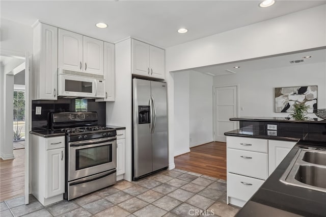 6515 Amigo Ave, Reseda, CA 91335 - kitchen with appliances with stainless steel finishes, dark countertops, white cabinets, recessed lighting, and light stone finish flooring