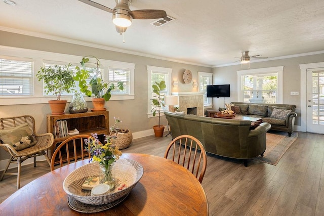 1396 N Ferger Ave, Fresno, CA 93728 - dining space with a ceiling fan, a tiled fireplace, crown molding, and light wood-type flooring