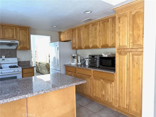 2227 Langspur Dr, Hacienda Heights, CA 91745 - kitchen featuring white appliances, under cabinet range hood, dark stone countertops, light tile patterned flooring, and recessed lighting