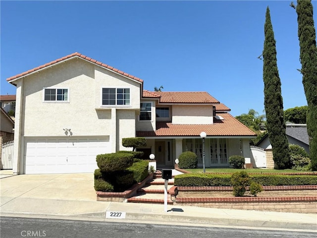 2227 Langspur Dr, Hacienda Heights, CA 91745 - mediterranean / spanish-style house featuring a garage, concrete driveway, french doors, a tile roof, and stucco siding
