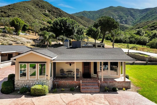 18310 Canon St, Devore, CA 92407 - view of front of house with a mountain view, covered porch, a front lawn, stone siding, and a shingled roof