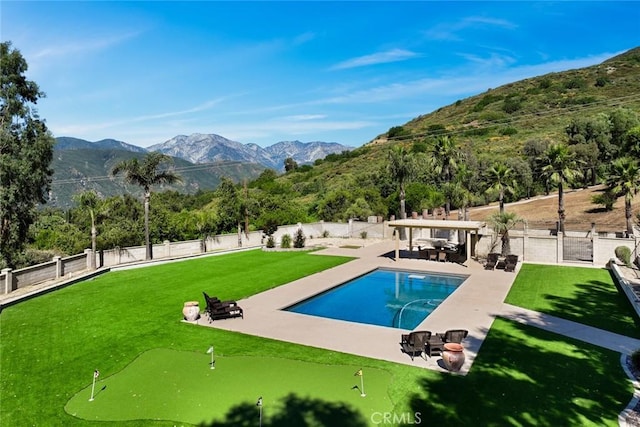 18310 Canon St, Devore, CA 92407 - view of swimming pool with an area to practice putting, a mountain view, a patio, and a fenced backyard