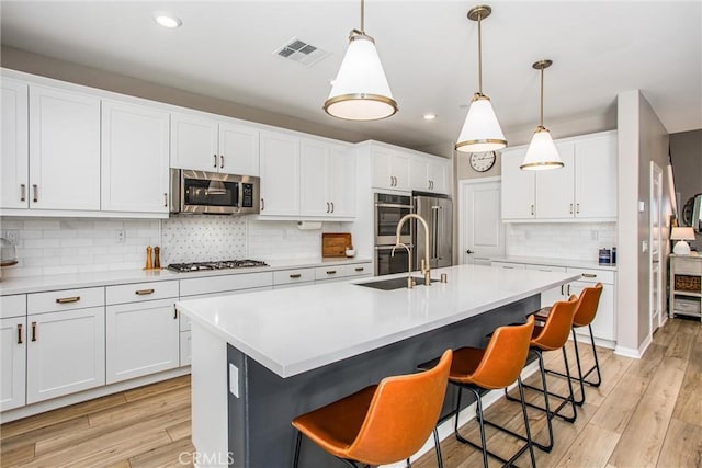 849 Half Moon Ave, Redlands, CA 92374 - kitchen featuring appliances with stainless steel finishes, backsplash, a kitchen bar, recessed lighting, and white cabinetry
