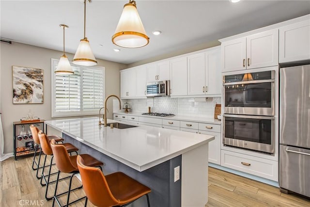 849 Half Moon Ave, Redlands, CA 92374 - kitchen with stainless steel appliances, tasteful backsplash, a kitchen bar, light wood finished floors, and light countertops