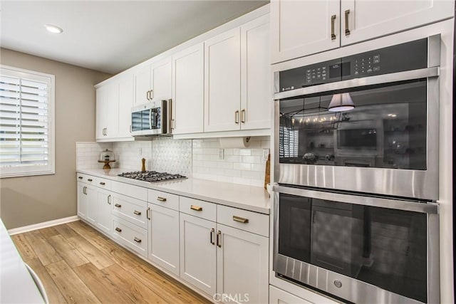 849 Half Moon Ave, Redlands, CA 92374 - kitchen featuring stainless steel appliances, light countertops, light wood-type flooring, tasteful backsplash, and white cabinets
