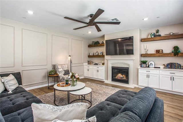 849 Half Moon Ave, Redlands, CA 92374 - living room featuring a ceiling fan, light wood-type flooring, a glass covered fireplace, recessed lighting, and a decorative wall