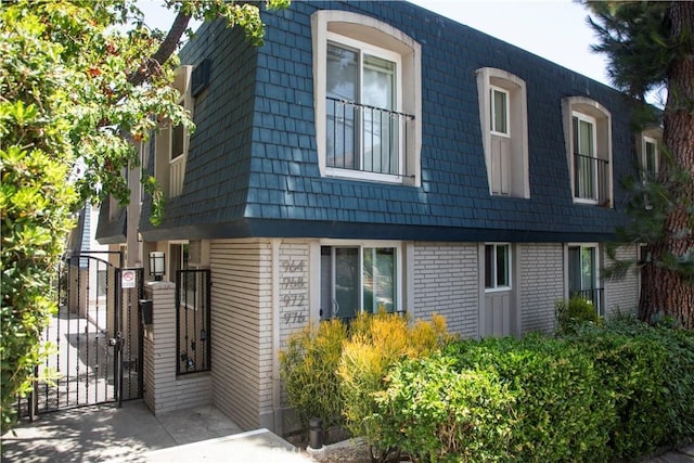 972 Larrabee St Unit 119, West Hollywood, CA 90069 - view of side of property with mansard roof, brick siding, and a gate