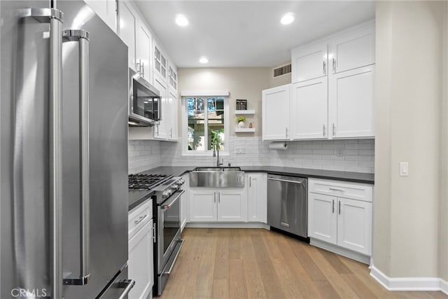 22 Brassie Ln, Coto De Caza, CA 92679 - kitchen with appliances with stainless steel finishes, dark countertops, recessed lighting, white cabinets, and light wood-type flooring