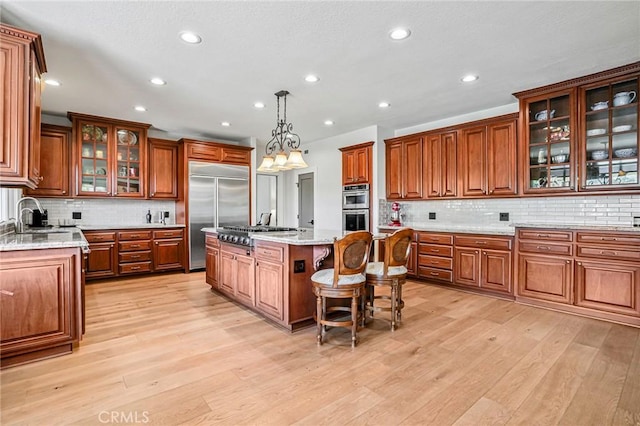 25291 Derbyhill Dr, Laguna Hills, CA 92653 - kitchen featuring stainless steel appliances, brown cabinets, decorative backsplash, light wood-type flooring, and recessed lighting