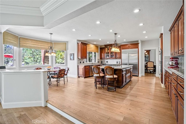 25291 Derbyhill Dr, Laguna Hills, CA 92653 - kitchen with stainless steel appliances, a kitchen island, a kitchen bar, ornamental molding, and recessed lighting