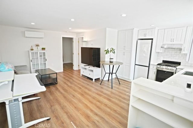 5525 Costello Ave, Sherman Oaks, CA 91401 - kitchen with gas stove, freestanding refrigerator, under cabinet range hood, an AC wall unit, and light wood-style floors