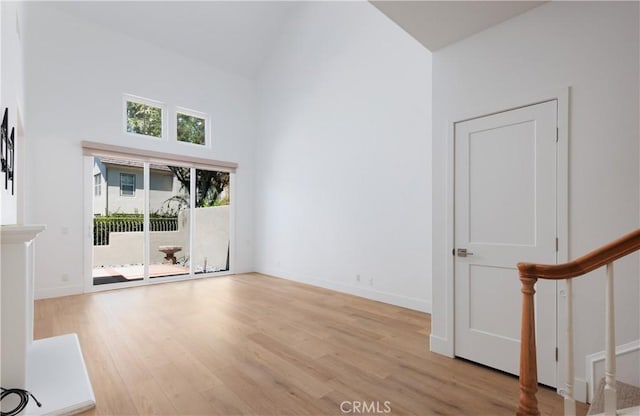 3 Longbourn Aisle, Irvine, CA 92603 - unfurnished living room with high vaulted ceiling, light wood-style flooring, and stairs