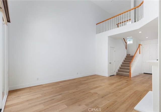 3 Longbourn Aisle, Irvine, CA 92603 - unfurnished living room with stairway, light wood-type flooring, recessed lighting, and a towering ceiling