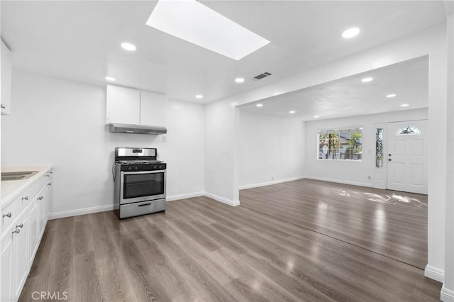 3310 Mangum St, Baldwin Park, CA 91706 - kitchen featuring stainless steel gas range, under cabinet range hood, recessed lighting, wood finished floors, and white cabinets