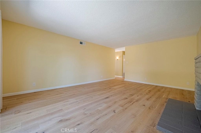 2601 Hoover Ct, Merced, CA 95340 - unfurnished room featuring light wood-style floors, a fireplace, and a textured ceiling