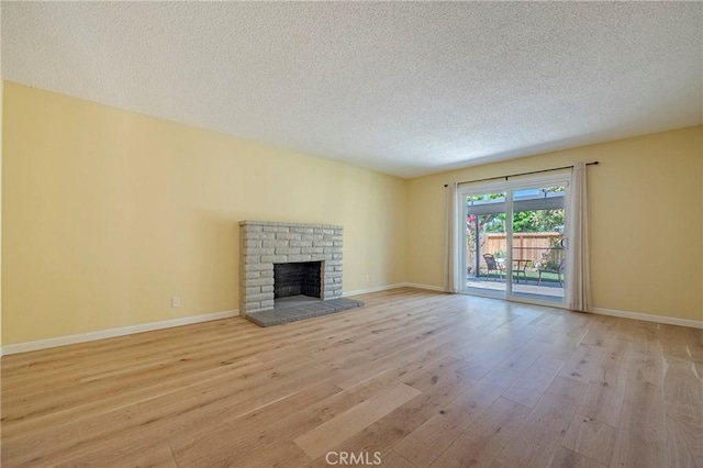 2601 Hoover Ct, Merced, CA 95340 - unfurnished living room featuring light wood-style floors, a textured ceiling, and a brick fireplace