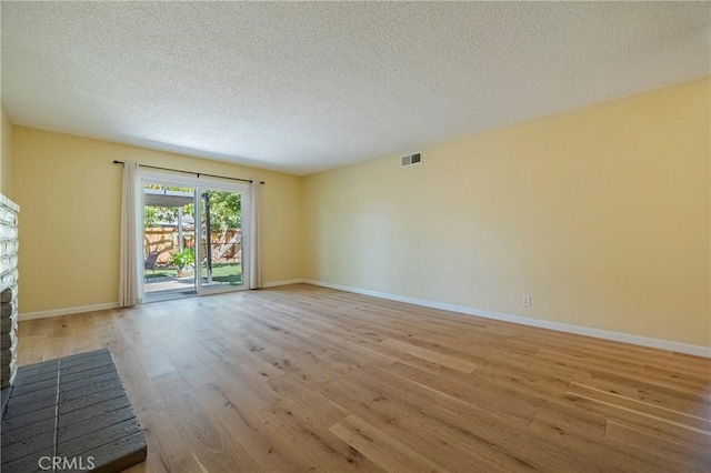 2601 Hoover Ct, Merced, CA 95340 - unfurnished living room with light wood-style floors, a textured ceiling, and a fireplace