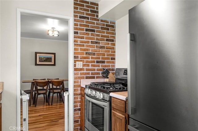 886 Lynn Ln, Chico, CA 95926 - kitchen with appliances with stainless steel finishes, wood finished floors, brown cabinetry, ornamental molding, and light countertops