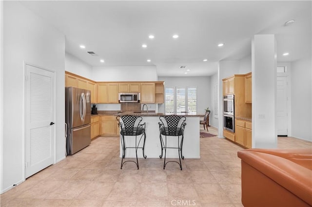 44397 Mesquite Dr, Indian Wells, CA 92210 - kitchen featuring appliances with stainless steel finishes, light brown cabinetry, a breakfast bar, recessed lighting, and an island with sink
