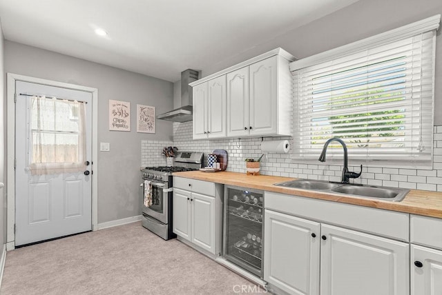 8213 Strub Ave, Whittier, CA 90602 - kitchen with stainless steel range with gas stovetop, wall chimney range hood, beverage cooler, wood counters, and light colored carpet
