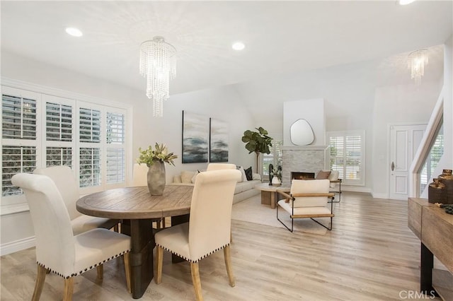 9552 Castine Dr, Huntington Beach, CA 92646 - dining area featuring a chandelier, light wood finished floors, a fireplace, recessed lighting, and vaulted ceiling