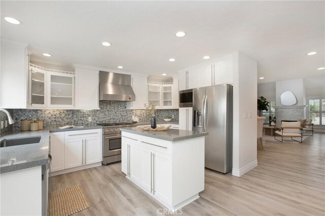 9552 Castine Dr, Huntington Beach, CA 92646 - kitchen with wall chimney range hood, appliances with stainless steel finishes, tasteful backsplash, light wood-type flooring, and recessed lighting