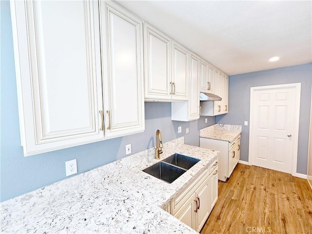 15951 M St, Mojave, CA 93501 - kitchen with under cabinet range hood, light stone counters, light wood-style floors, and white cabinetry