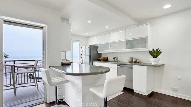 1202 N Pacific St Unit 203A, Oceanside, CA 92054 - kitchen featuring stainless steel dishwasher, freestanding refrigerator, modern cabinets, a kitchen bar, and white cabinetry