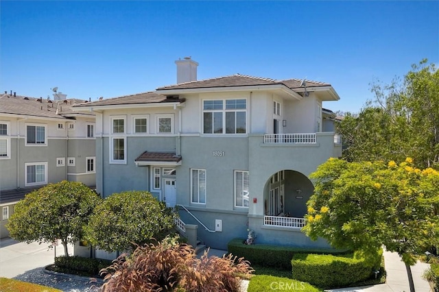 18051 Joyful Ln Unit 201, Huntington Beach, CA 92648 - view of front of property with a chimney, stucco siding, a balcony, and a tiled roof