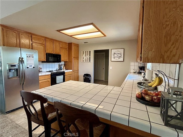 42445 Deep Forest Dr, Coarsegold, CA 93614 - kitchen featuring black appliances, tile countertops, decorative backsplash, and a peninsula