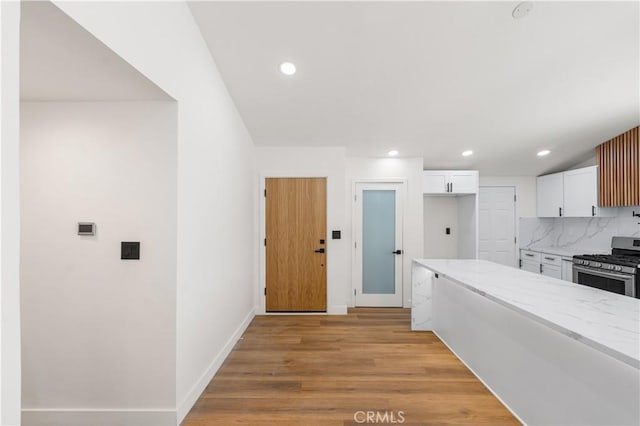 18718 Delight St, Canyon Country, CA 91351 - kitchen featuring stainless steel gas range oven, light stone countertops, white cabinets, light wood-style floors, and backsplash