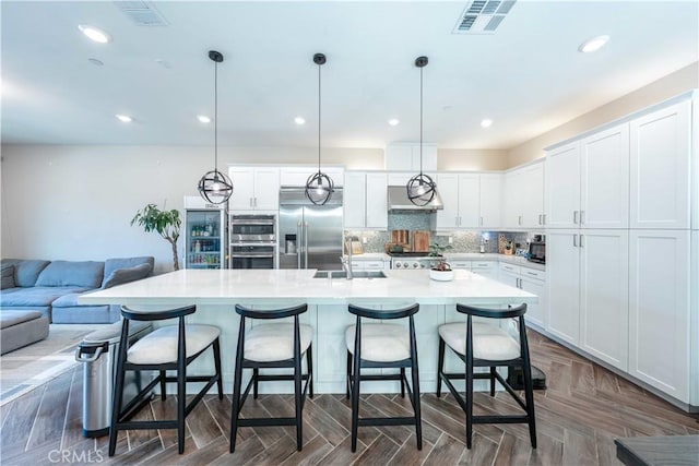 143 Interval, Irvine, CA 92618 - kitchen featuring appliances with stainless steel finishes, a kitchen bar, light countertops, white cabinetry, and extractor fan