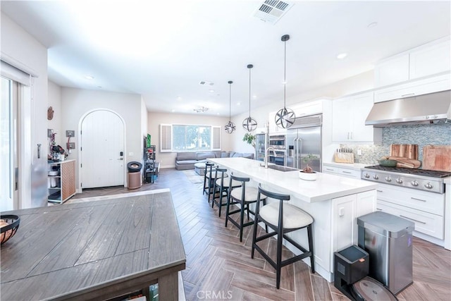 143 Interval, Irvine, CA 92618 - kitchen featuring stainless steel appliances, ventilation hood, open floor plan, a center island with sink, and a kitchen bar