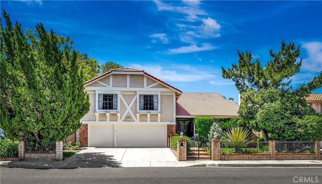 11830 Killimore Ave, Porter Ranch, CA 91326 - tudor home featuring an attached garage, concrete driveway, a fenced front yard, stucco siding, and a tiled roof