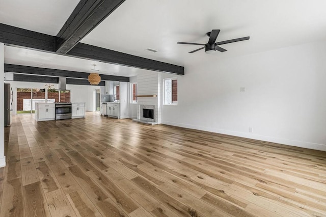 3167 Camarillo Ave, Oceanside, CA 92056 - unfurnished living room with light wood finished floors, ceiling fan, beamed ceiling, and a fireplace with raised hearth