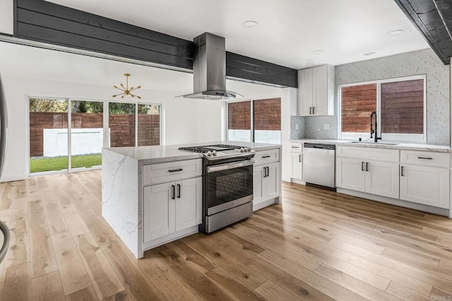 3167 Camarillo Ave, Oceanside, CA 92056 - kitchen with stainless steel appliances, island range hood, light wood-style floors, and white cabinetry