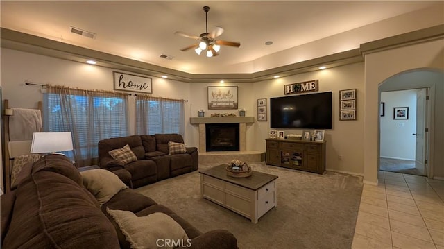 3242 Ashbury Ave, Madera, CA 93637 - living area with arched walkways, ceiling fan, a fireplace with raised hearth, light tile patterned floors, and light colored carpet
