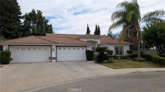 3242 Ashbury Ave, Madera, CA 93637 - mediterranean / spanish-style house featuring concrete driveway, a tiled roof, an attached garage, stucco siding, and a front yard