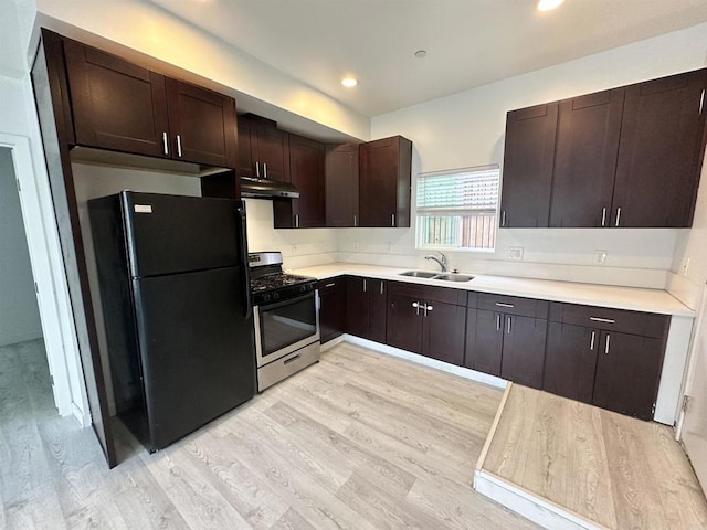 550206 E University Ave, San Diego, CA 92105 - kitchen with freestanding refrigerator, stainless steel range with gas cooktop, under cabinet range hood, light wood-style floors, and dark brown cabinetry