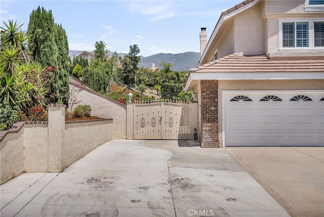 13982 Claremont Ln, Rancho Cucamonga, CA 91739 - view of side of property featuring driveway, stucco siding, a chimney, brick siding, and a tile roof