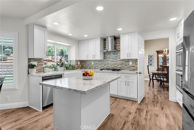 13982 Claremont Ln, Rancho Cucamonga, CA 91739 - kitchen featuring wall chimney range hood, appliances with stainless steel finishes, light wood finished floors, white cabinetry, and recessed lighting