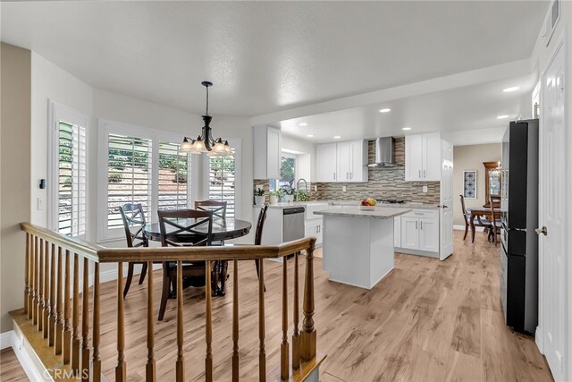13982 Claremont Ln, Rancho Cucamonga, CA 91739 - kitchen with wall chimney range hood, stainless steel appliances, a center island, white cabinetry, and light wood-style flooring
