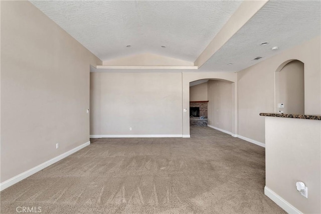 15090 Olema Rd, Apple Valley, CA 92307 - carpeted spare room featuring lofted ceiling, a fireplace, a textured ceiling, and arched walkways