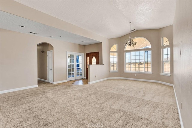 15090 Olema Rd, Apple Valley, CA 92307 - carpeted empty room with a textured ceiling, vaulted ceiling, a chandelier, arched walkways, and french doors