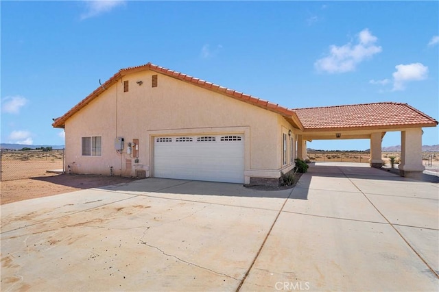 15090 Olema Rd, Apple Valley, CA 92307 - view of side of property featuring an attached garage, concrete driveway, stucco siding, and a tiled roof