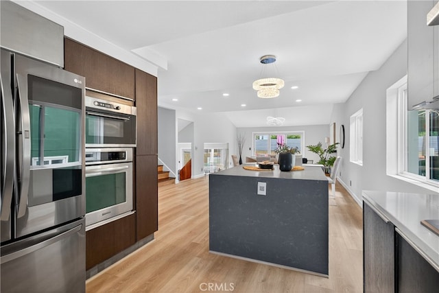 913 Lindencliff St, Torrance, CA 90502 - kitchen with stainless steel appliances, light wood-style flooring, dark brown cabinets, decorative light fixtures, and a center island