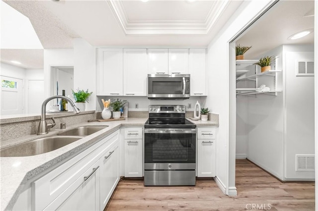 45 Briarglen Unit 64, Irvine, CA 92614 - kitchen with stainless steel appliances, ornamental molding, white cabinets, a tray ceiling, and light wood-type flooring