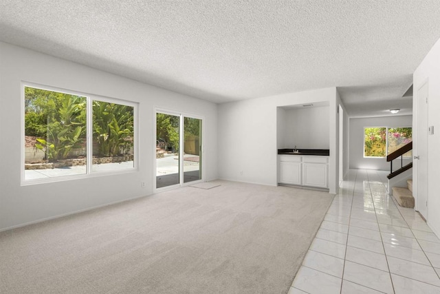 13443 Black Hills Rd, San Diego, CA 92129 - unfurnished living room featuring plenty of natural light, stairs, a textured ceiling, light colored carpet, and light tile patterned floors