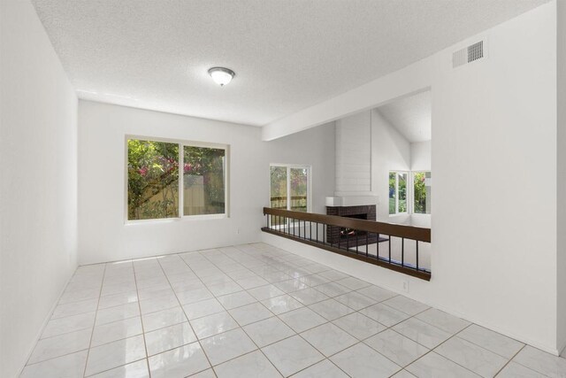13443 Black Hills Rd, San Diego, CA 92129 - spare room featuring a brick fireplace, light tile patterned floors, and a textured ceiling