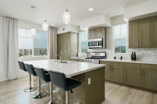 2850 Wagon Wheel Rd Unit 402, Oxnard, CA 93036 - kitchen featuring appliances with stainless steel finishes, a breakfast bar area, light wood-type flooring, and tasteful backsplash
